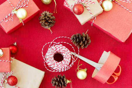 Preparing for the holiday - gift wrapping in red and beige wrapping paper.