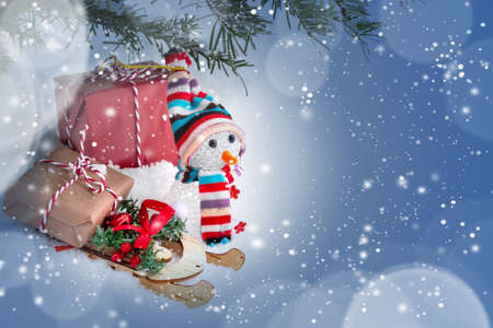 Christmas composition under the Christmas tree - a snowman, boxes with gifts on a sled and other decorations, place for text, copy spaceの写真素材