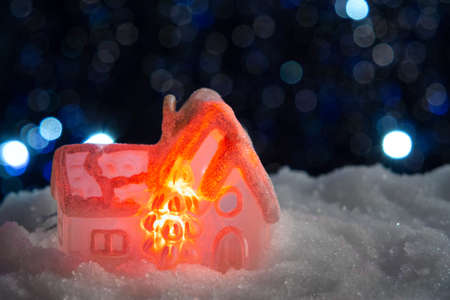 Glowing toy house in the snow on the background of Christmas lights. Festive, Christmas or New Year conceptの写真素材