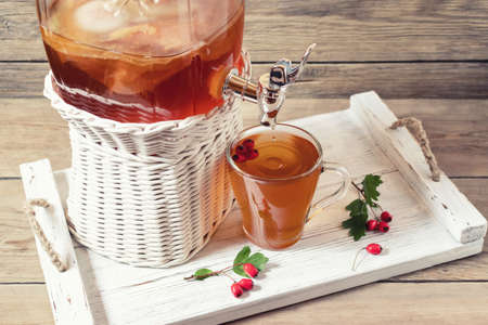 Fresh homemade kombucha fermented tea drink in a jar with faucet and in a cup on a white tray with...