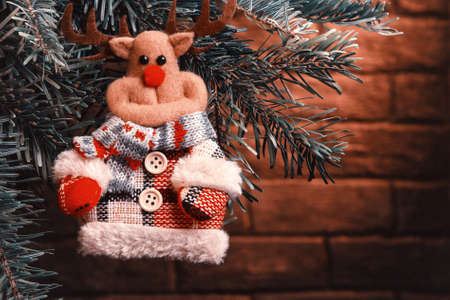 Fabric toy deer on Christmas tree on Christmas eve, place for text, copy spaceの写真素材