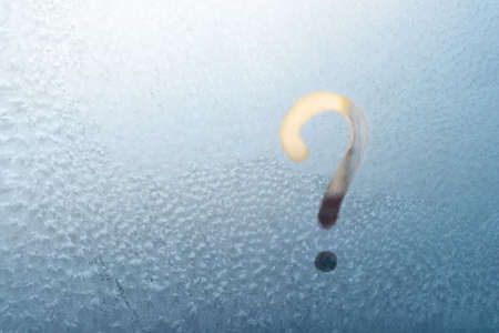 Question mark hand written on a frozen window, place for text, copyspace