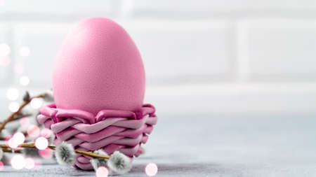 Pink Easter egg in a wicker stand on a gray table with pussy-willow twigs - Easter composition with copy space, horizontal bannerの写真素材