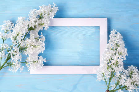 Spring or summer floral background for greeting card. White lilac and wooden frame on a blue background. Template for design with copy space.の写真素材
