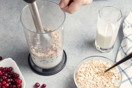 Making homemade smoothie with yoguot, cranberries and oatmeal. Beating a blender for healthy and wholesome nutrition.の写真素材