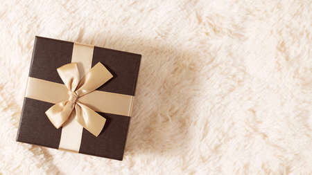 Beautiful golden box on cream fur blanket. Surprises, gifts, bonuses, discounts concept. Blank for...