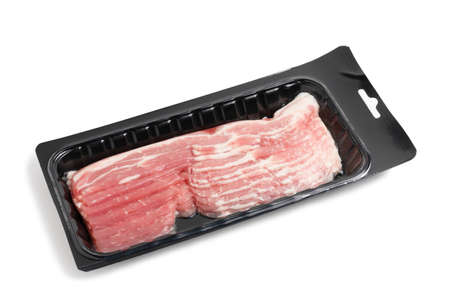 Slices of raw bacon in black vacuum packaging isolated on a white backgroundの写真素材