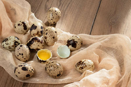 Composition of several quail eggs on decorative fabric on a wooden table close-up, flatlay