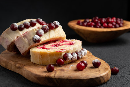 Homemade biscuit sweet roll with cranberries and cream on a black tableの写真素材