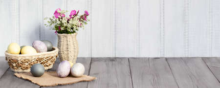 Easter composition - several eggs painted with natural dyes and wildflowers in a vaseの写真素材