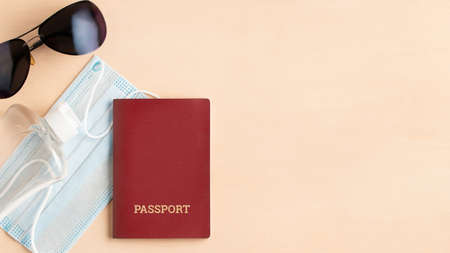 Safe travel during pandemic concept. Protective medical mask, sunglasses, sanitizer and passport on...