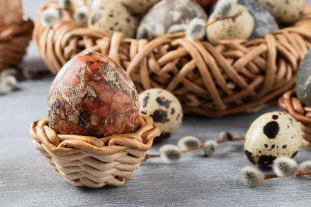 Easter composition - several marble eggs painted with natural dyes in a wicker nest and basketsの写真素材