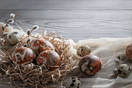 Easter composition - several marble eggs painted with natural dyes in a paper nest on the table, copy spaceの写真素材