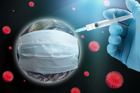 Coronavirus global vaccination concept. Earth in a protective mask, hand with a syringe makes an injection.の写真素材