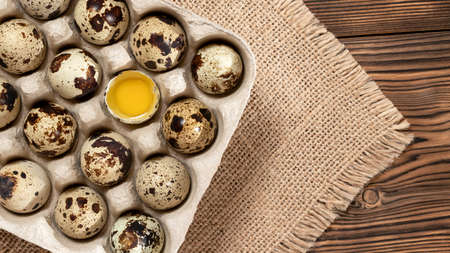 Quail eggs in cardboard packaging on a wooden table, copy space, horizontal banner, flatlayの写真素材