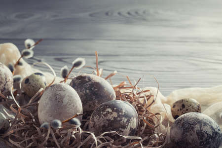 Easter composition - several marble eggs painted with natural dyes in a paper nest on the table, copy spaceの写真素材
