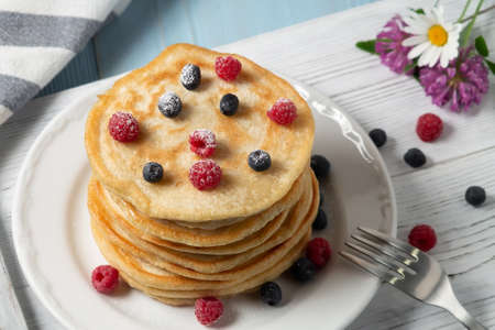 Stack of pancakes with fresh berries on a white plate on the tableの写真素材