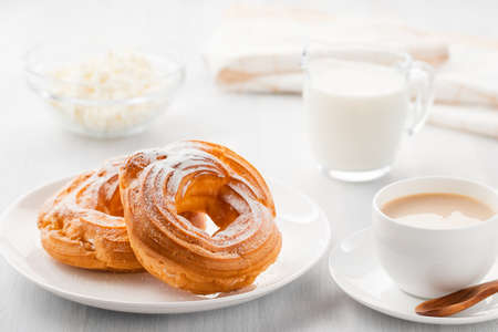 Morning coffee with cake. Custard rings, coffee, cream, cottage cheese on a white wooden table