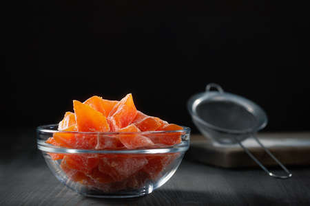 Natural farm homemade candied pumpkin fruits sprinkled with powdered sugar in a glass bowl on a wooden tableの写真素材