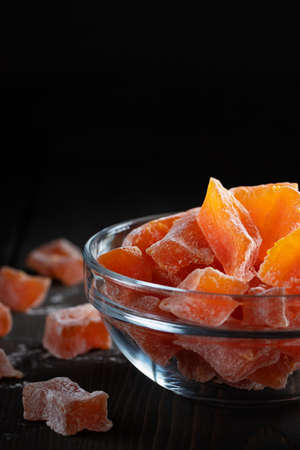Natural farm homemade candied pumpkin fruits sprinkled with powdered sugar in a glass bowl on a wooden tableの写真素材