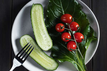 Fresh vegetables and herbs in a plate on a wooden table. Concept of vegetarianism and healthy eatingの写真素材