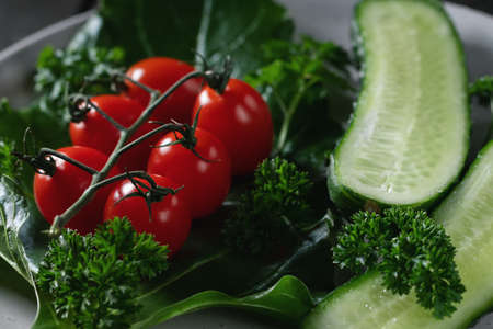Fresh vegetables and herbs in a plate on a wooden table. Concept of vegetarianism and healthy eatingの写真素材