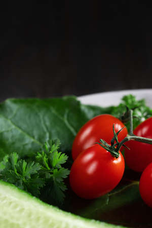 Fresh vegetables and herbs in a plate on a wooden table. Concept of vegetarianism and healthy eating. Copyspace.の写真素材