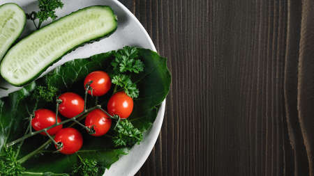 Fresh vegetables and herbs in a plate on a wooden table. Concept of vegetarianism and healthy eating. Copyspace.の写真素材