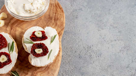 Homemade sandwiches with cream cheese and sun-dried tomatoes on a wooden board of olive - delicious...