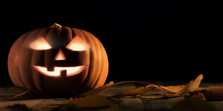 Halloween pumpkin head jack lantern with glowing eyes on wooden tableの写真素材