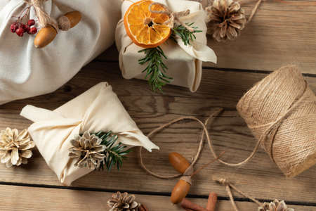 Zero waste christmas concept. Packed in natural fabric gifts and decorations from natural materials on a wooden tableの写真素材