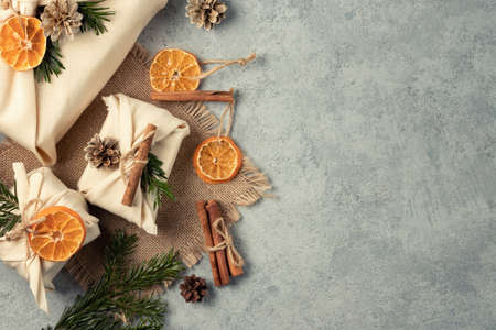 Zero waste christmas concept. Packed in natural fabric gifts and decorations from natural materials on gray table, top view, copy spaceの写真素材