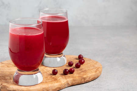 Two glasses with homemade freshly cranberry juice on a gray concrete tableの写真素材