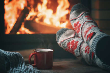 Girl resting and warming her feet by a burning fireplace in a country house on a winter eveningの写真素材