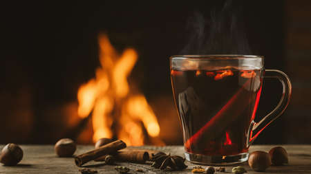 Glass mug with hot mulled wine by the burning fireplaceの写真素材