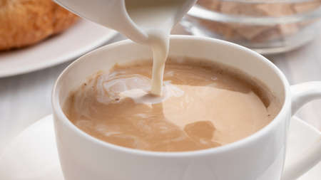 Pouring milk or cream into freshly brewed coffee, close upの写真素材