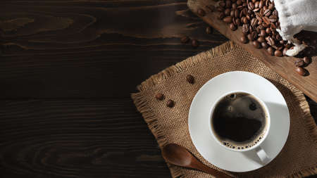 White cup of fresh hot coffee and coffee beans on the table, top view, flat lay, copyspace.の写真素材