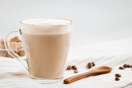 Latte coffee with foam on a light kitchen table, copy spaceの写真素材