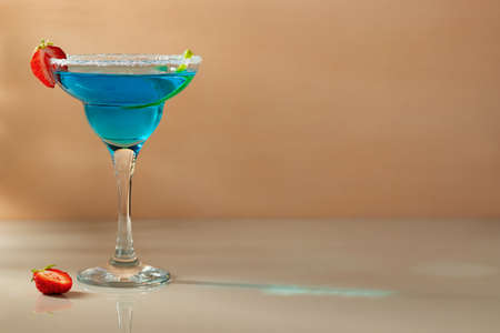 Glass with blue margarita cocktail garnished with lime zest and strawberries, selective focusの写真素材