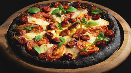 Black pizza with tomatoes, sausages, mozzarella and basil. Dough with healthy bamboo charcoal powderの写真素材