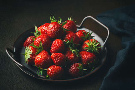 Ripe fresh farmed natural strawberries on a metal tray on the tableの写真素材