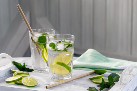 Summer refreshing mojito cocktails with lime and mint on a white wooden trayの写真素材