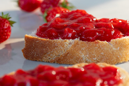 Wheat bread toasts with spread strawberry jam on the table, closeupの写真素材
