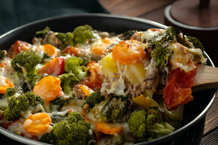 Gratin with broccoli, carrots and cheese baked in the oven on a dark wooden tableの写真素材