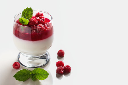 Panna cotta with raspberry jelly and mint leaves in glass glasses on a white table, copyspaceの写真素材