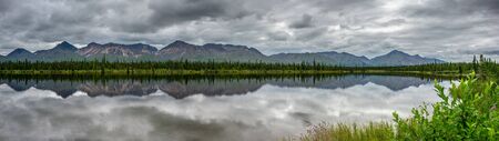 Alaska pine tree forest reflection on a lake under the clouds 32:9 ultrawideの写真素材