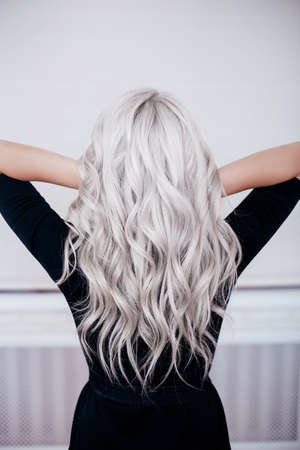 beautiful girl back with silver gray ash blonde curly wavy long hair in black dress isolated