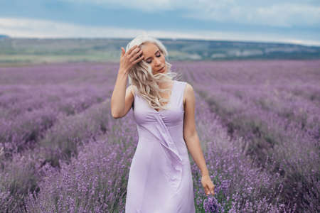 Beautiful blonde hair girl in violet dress in lavender fieldの写真素材