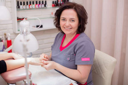 Manicure and nail care master working with client in beauty studio with happy smileの写真素材
