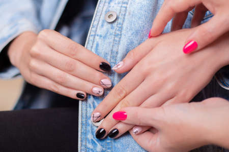 Manicurist holding female hands with fashion manicure nails, stylish design, nude and black gel polish for photoshootの写真素材